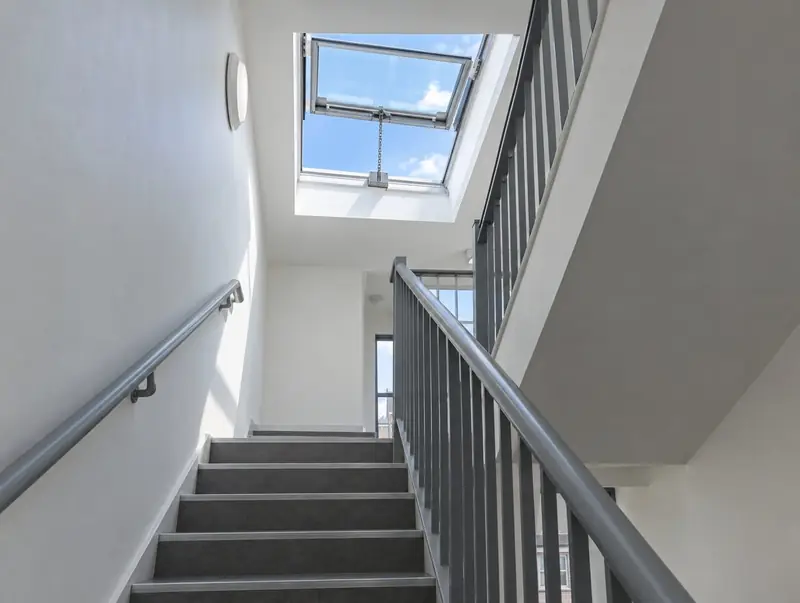 Smoke vent rooflight opened by a chain actuator at the top of a communal stairwell